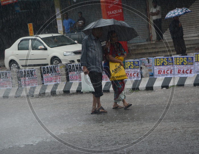 Pedestrians Drenching in  Heavy Rains And Walking  with Umbrellas on Hyderabad City Roads