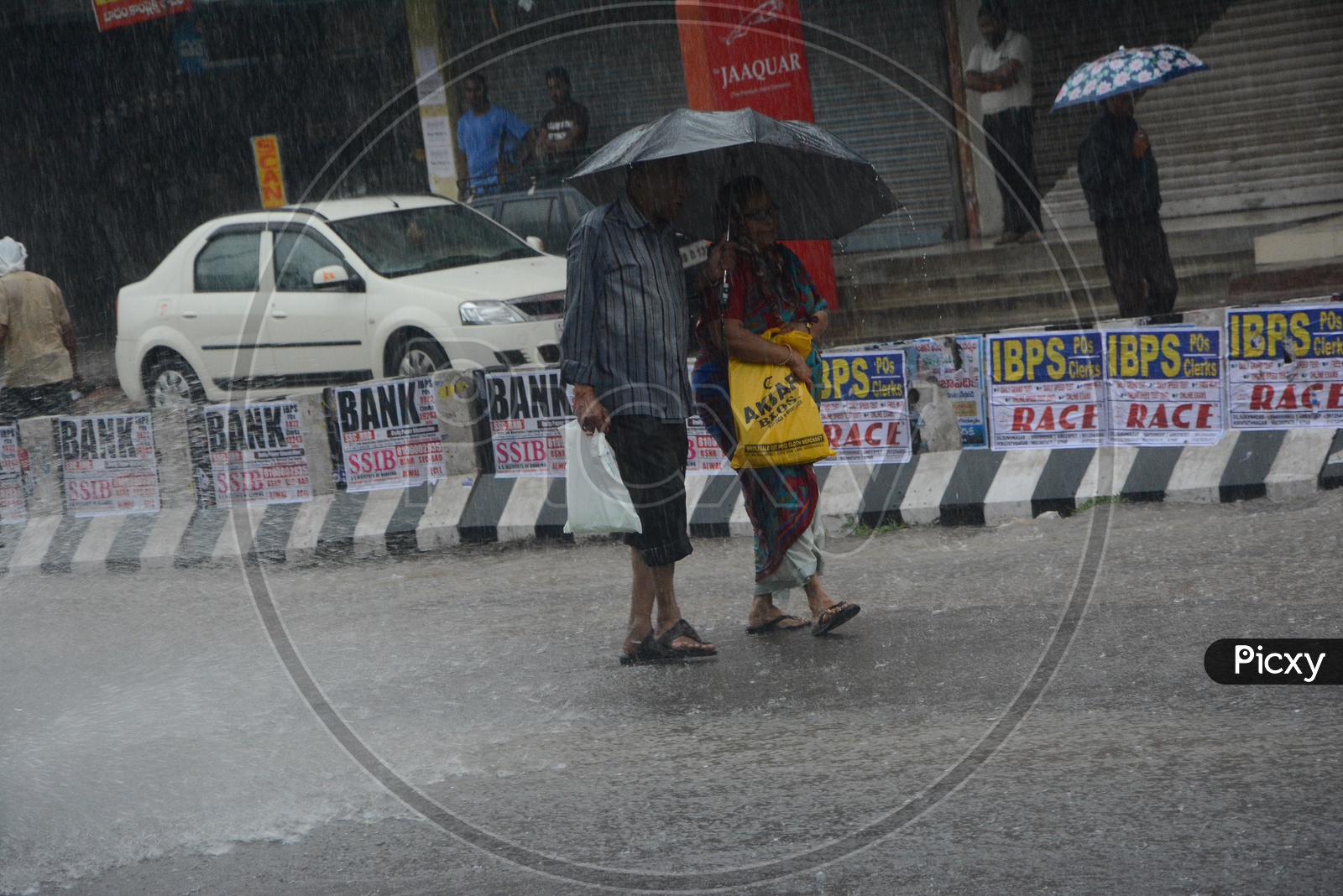 Pedestrians Drenching in  Heavy Rains And Walking  with Umbrellas on Hyderabad City Roads