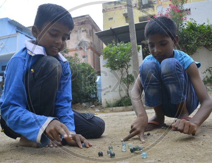 Indian Children Playing Marble Striking Game On Streets