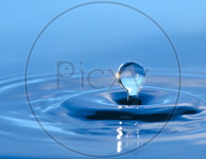 water splash With Droplet Over Blue Water Surface Closeup