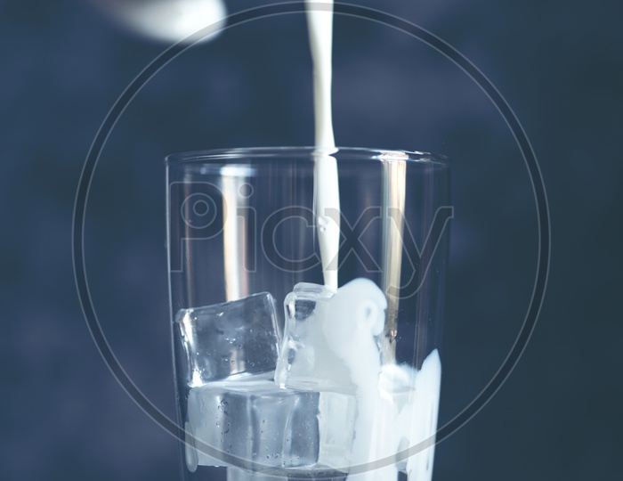 Pouring Milk into a Glass with Ice Cubes