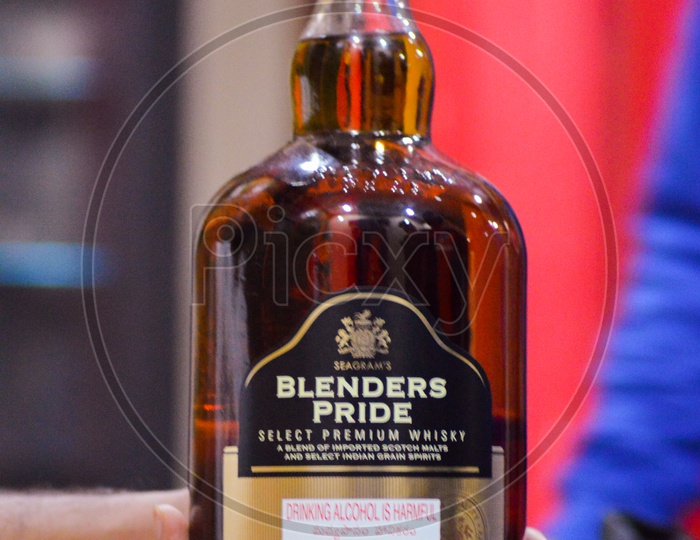A person holding a full bottle of the famous alcoholic beverage - Blenders Pride - BP