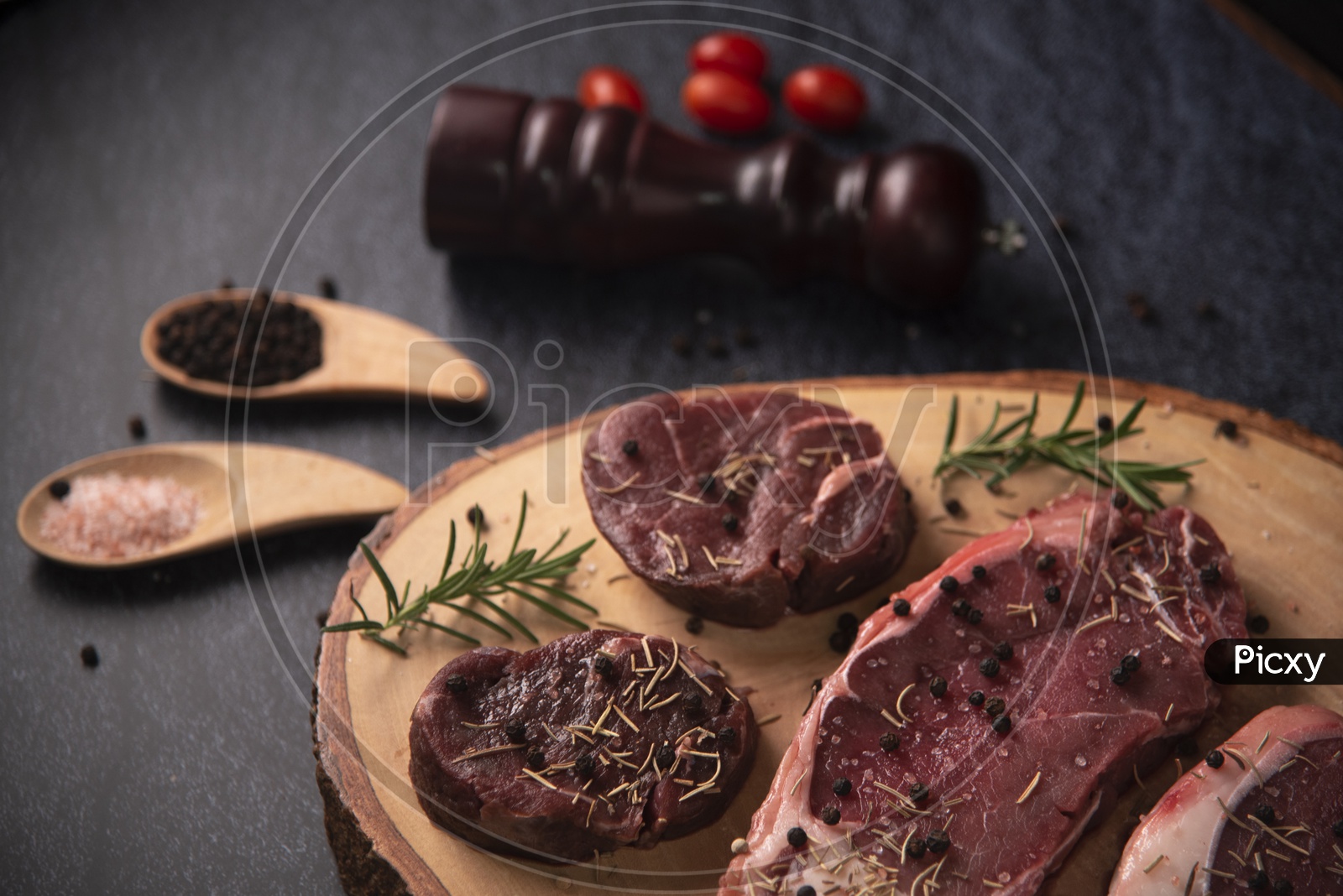 Pieces of Raw beef fillet steaks with spices on wooden background