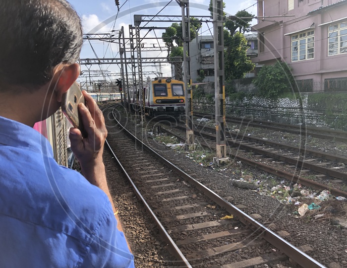 Indian Man Speaking In Phone While Travelling In  Mumbai Local Train Standing at Door Step