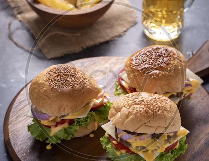 Top View of Delicious Beef Burgers on a Wooden Plate with Beer in Background