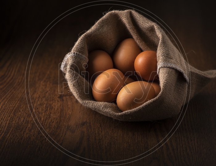 Fresh Brown Eggs in Sack Bag on Wooden Background