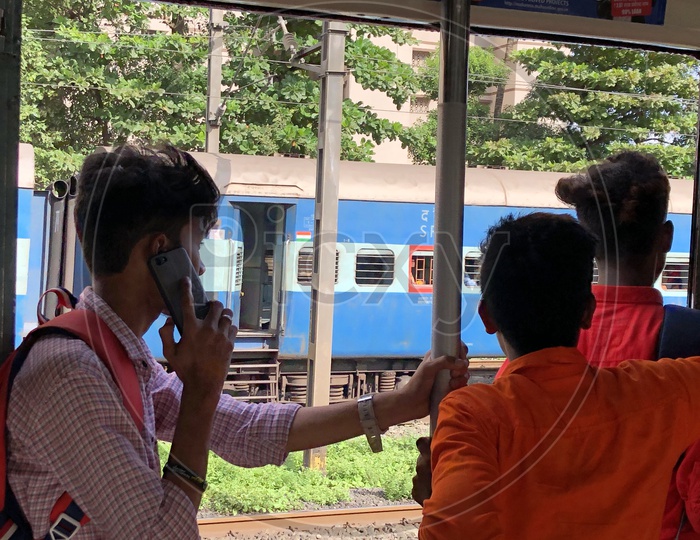 Young Student Speaking On Mobile  by Standing at Local Train Door Step
