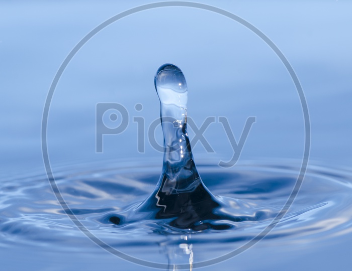 water splash With Droplet Over Blue Water Surface Closeup