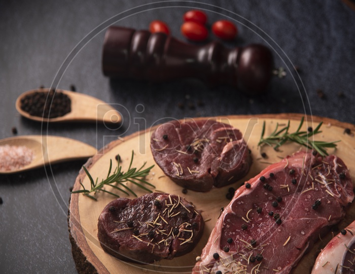 Pieces of Raw beef fillet steaks with spices on wooden background