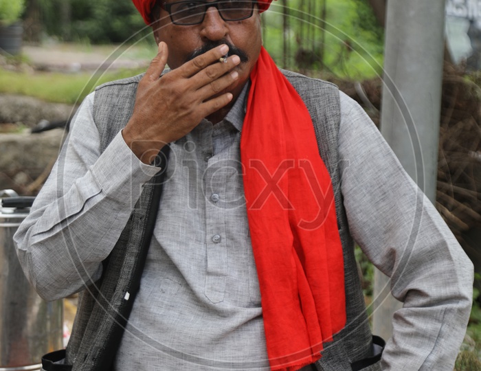 Indian Man wearing a red head scarf smoking a cigarette