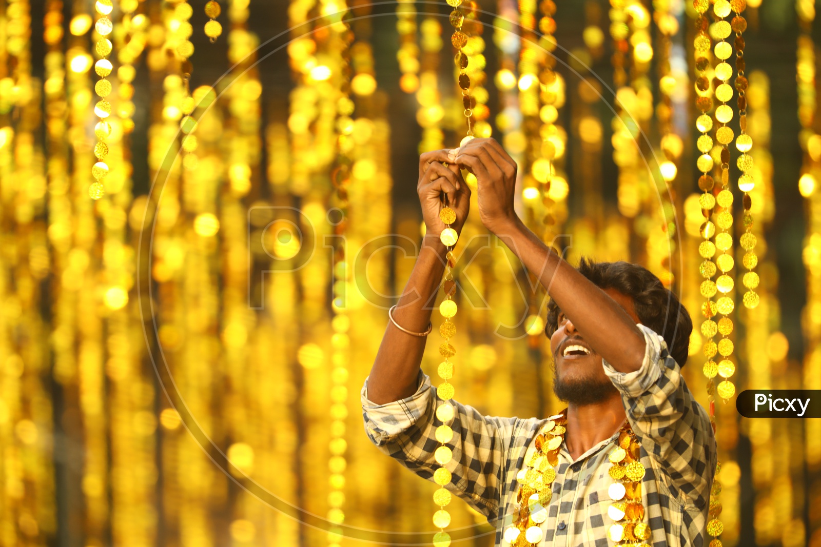 Indian Man connecting the hanging coin decorations  during the night