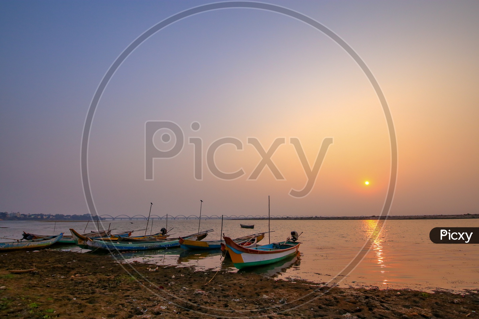 Fishing Boats At Godavari River Bank With Arch Bridge And Sunset Sky in Background
