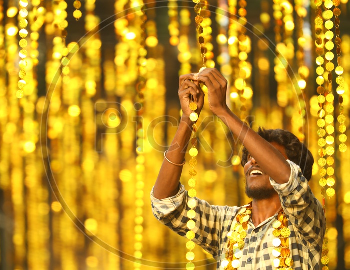 Indian Man connecting the hanging coin decorations  during the night