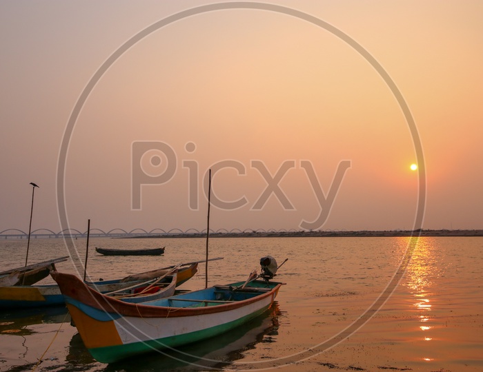 Fishing Boats At Godavari River Bank With Arch Bridge And Sunset Sky in Background