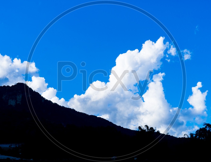 Blue Sky With Cotton Clouds Over a Mountain