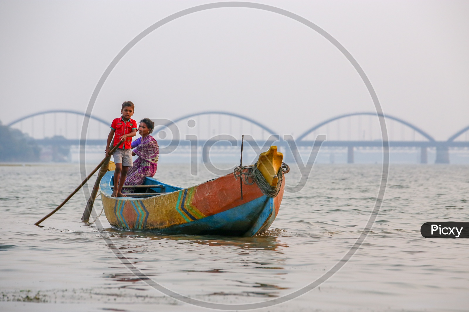Indian Mother And Son in a  Fishing Boat on River Godavari  With Rajahmundry Arch Bridge in Background