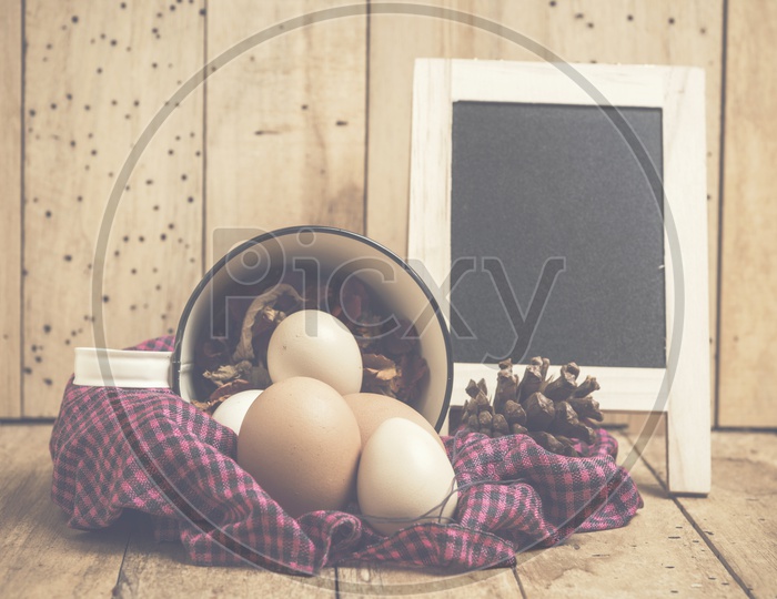 Easter Eggs In a Basket With Vintage Filter Over Wooden Backdrop