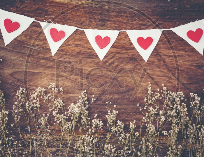 Dry grass and white flags with hearts frame on wood background