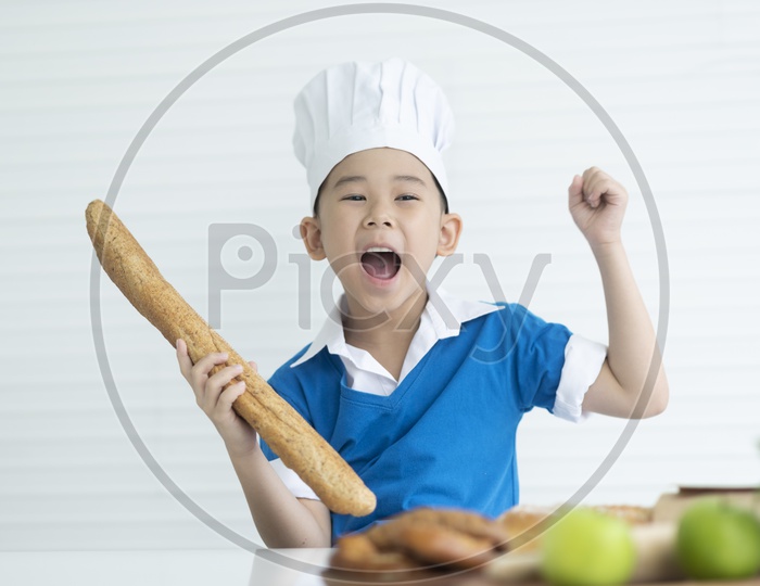 Boy as chef holding Italian long bread and enjoying cooking