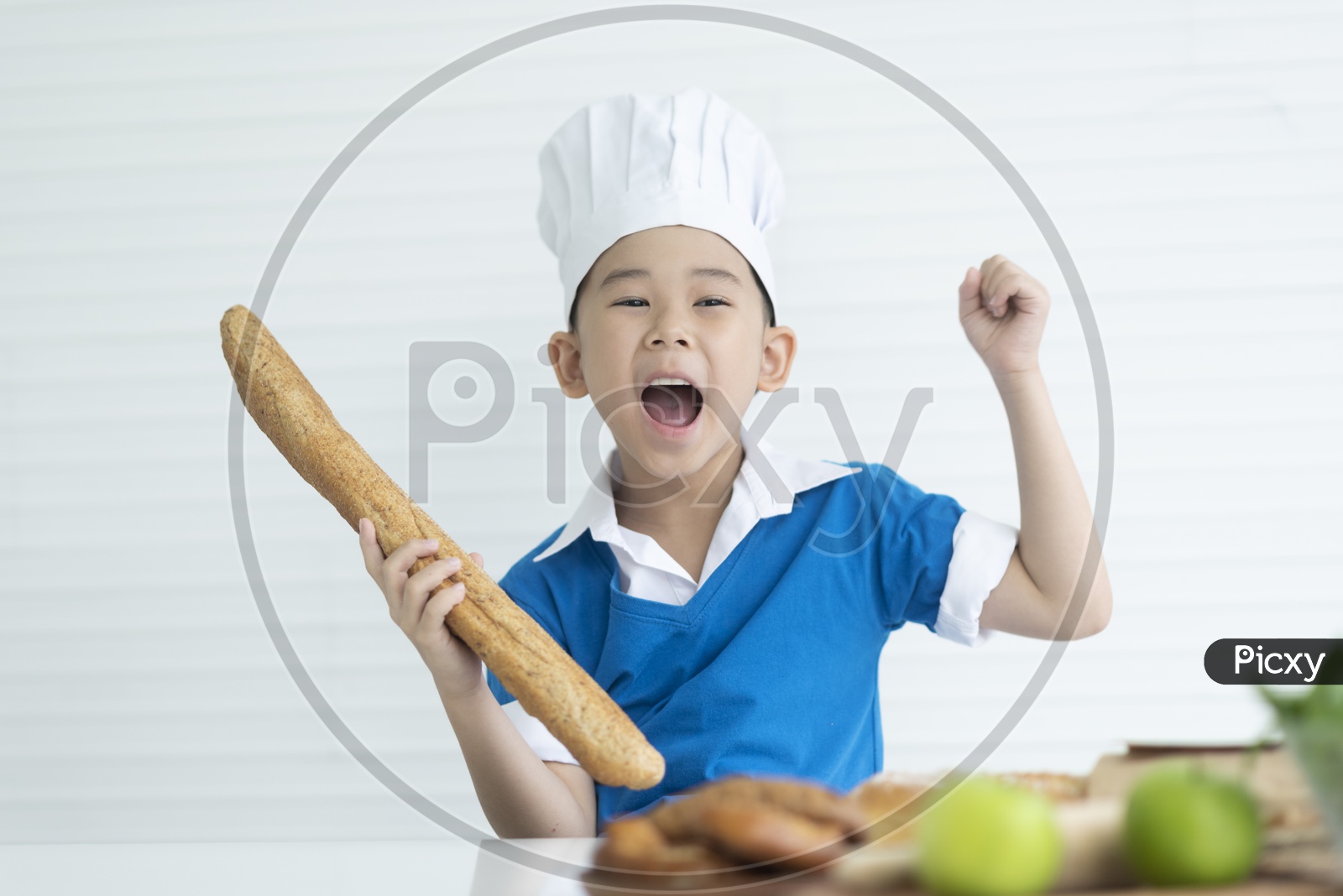 Boy as chef holding Italian long bread and enjoying cooking