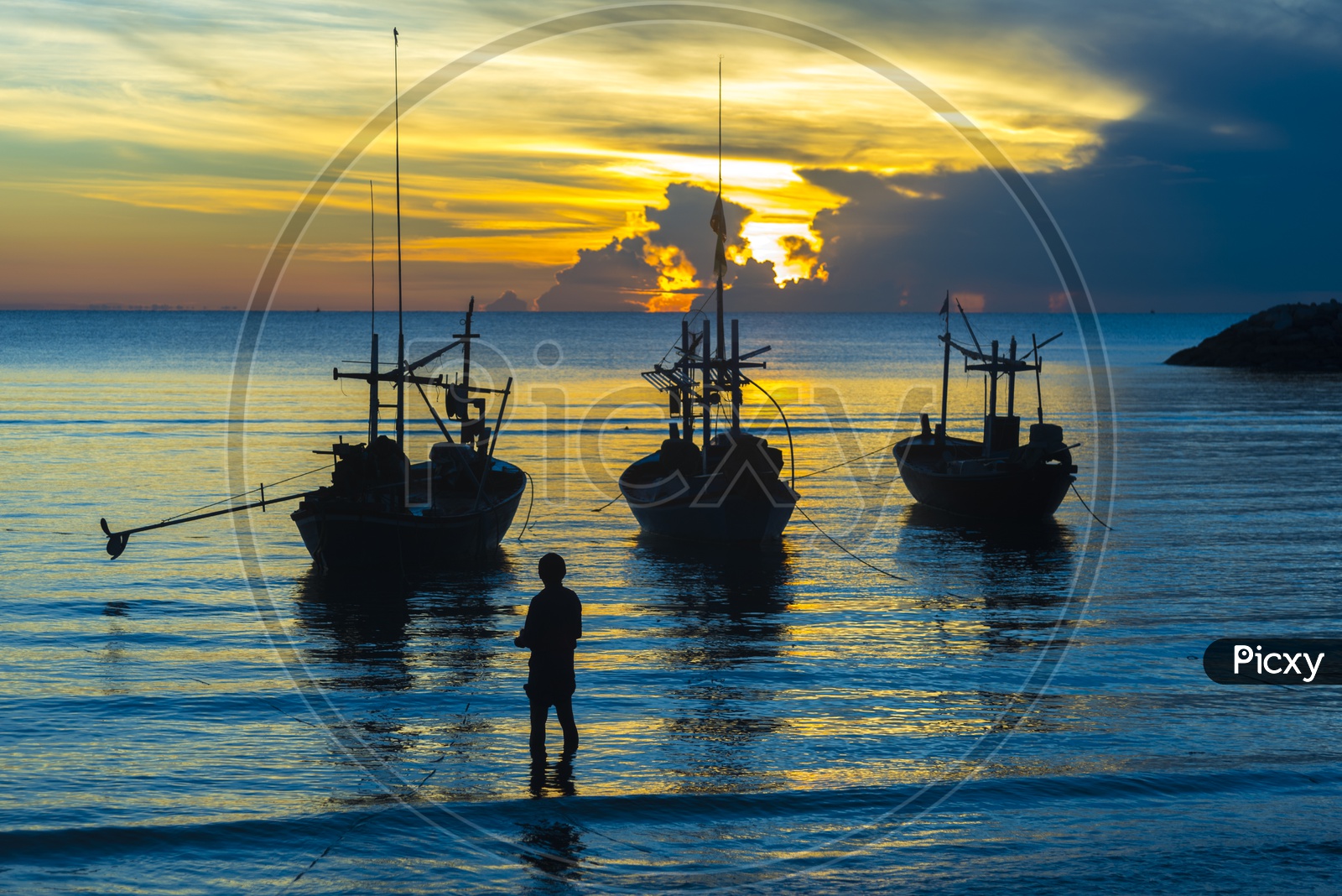 Silhouette Of Fishing Boats And Fisherman Carrying Their Catch Over a River With Blue Hour Sky in Background