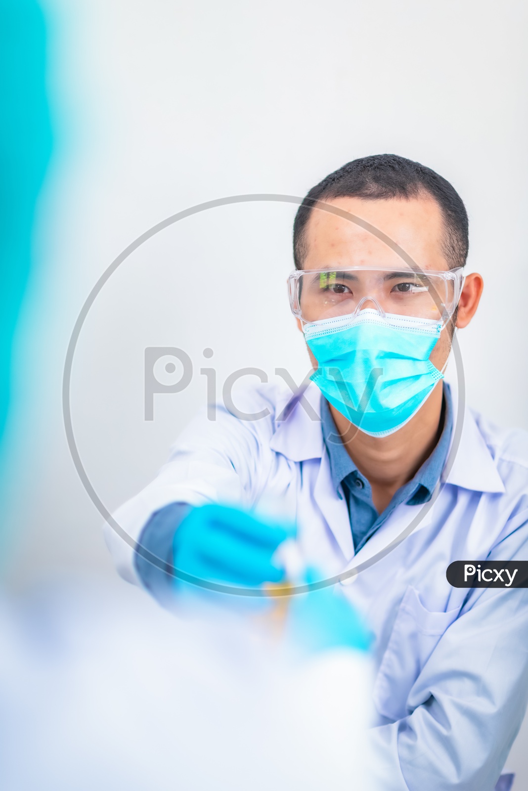 Research Scientist Performing Experiments In Laboratory  Wearing an Apron and Mask