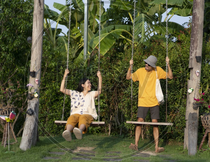 Women and men in yellow casual wear Playing in a Lawn With Swings