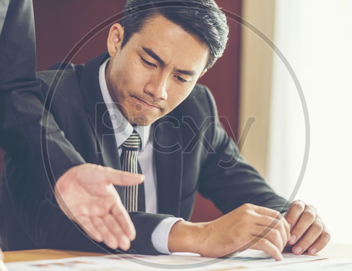 Professional man looking into the project documents shown by another person