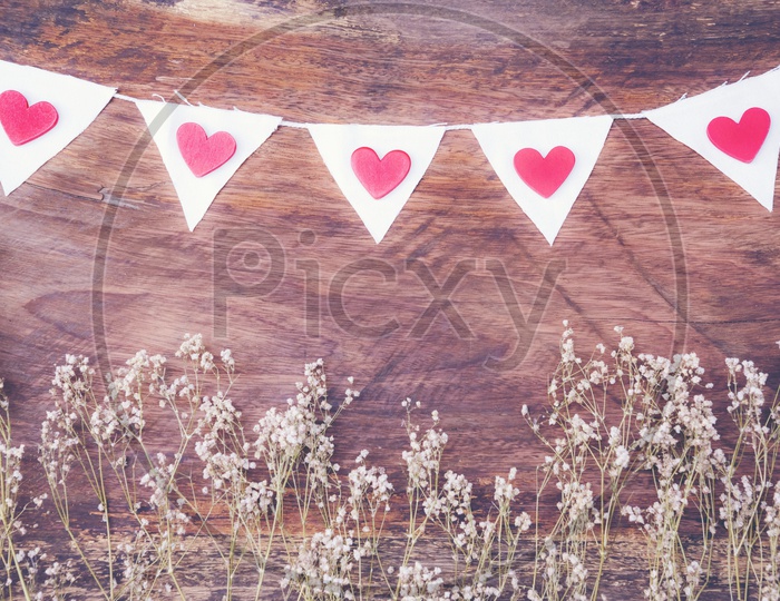 Dry grass and white flags with hearts frame on wood background