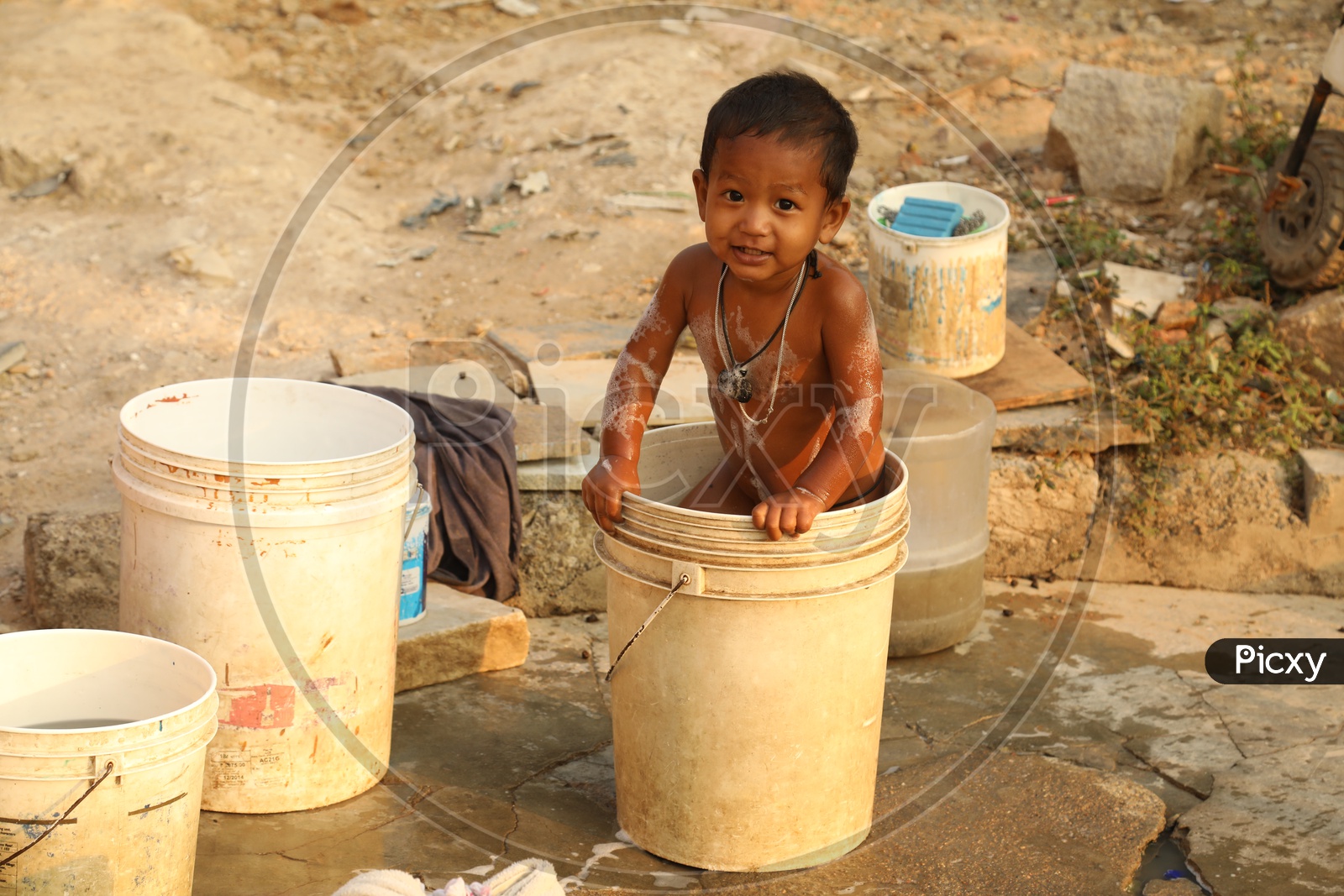 A Child playing with water in a bucket during bath