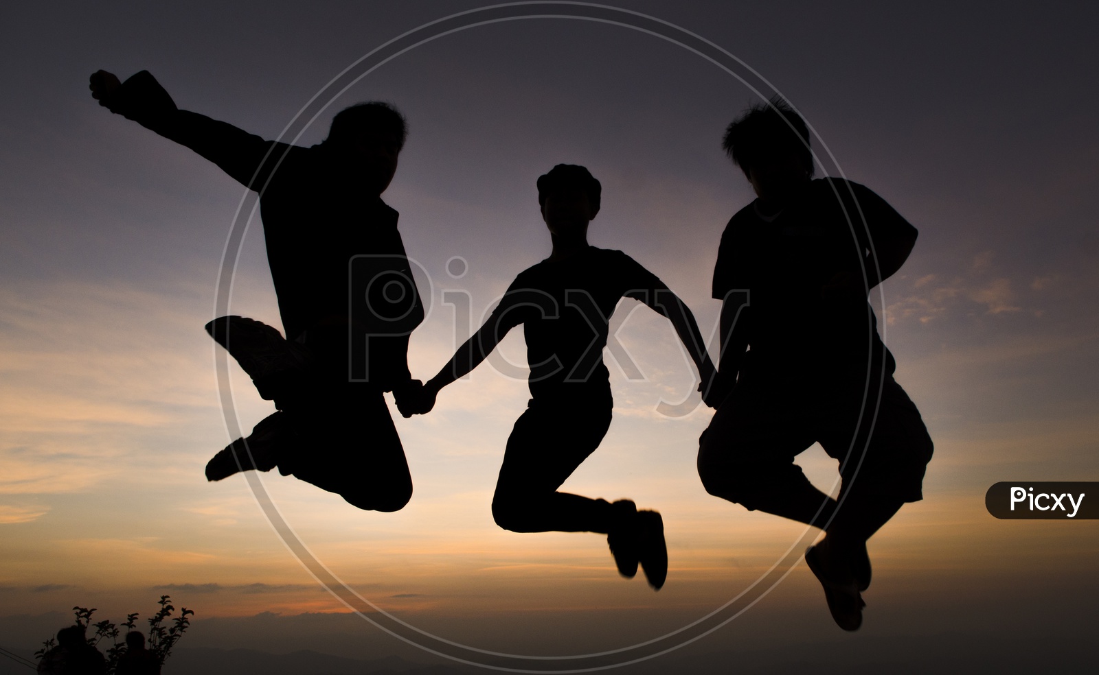 Silhouette of People Jumping In Joy Over a Sunset Sky