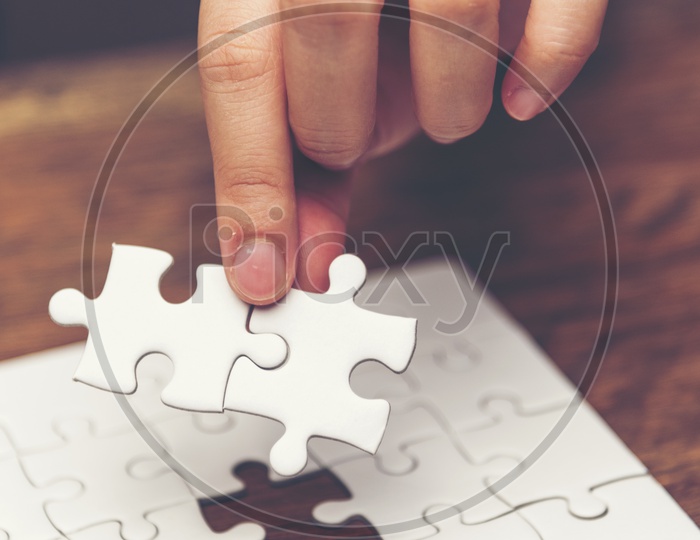 Close up of hand placing the jigsaw puzzle pieces, Hand holding missing jigsaw puzzle piece down in to the place, conceptual of problem solving, finding a solution