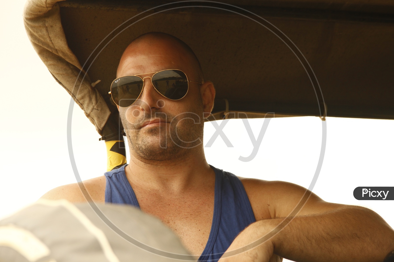 A stylish black man with a bald head and full beard, holding a phone and  sunglasses, standing against a wall in a light-colored jacket. The  selective Stock Photo - Alamy