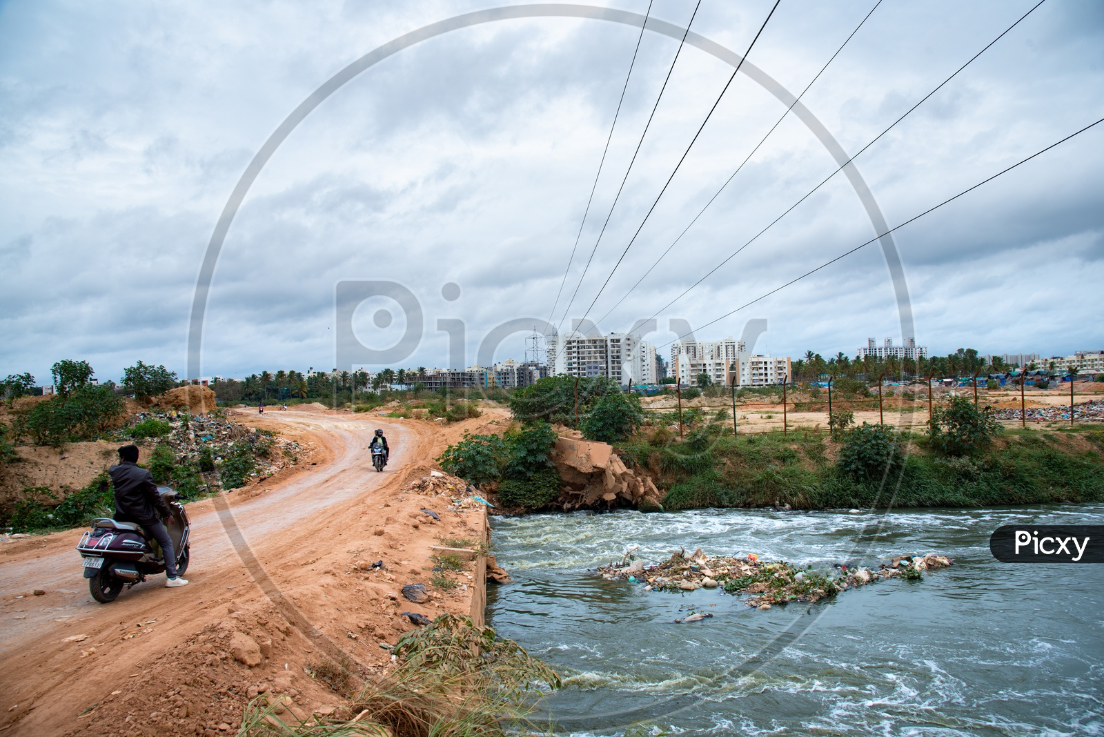 Bikes Commuting Over A Mud Road Built On a Sewage Water Canal at Tubarahalli