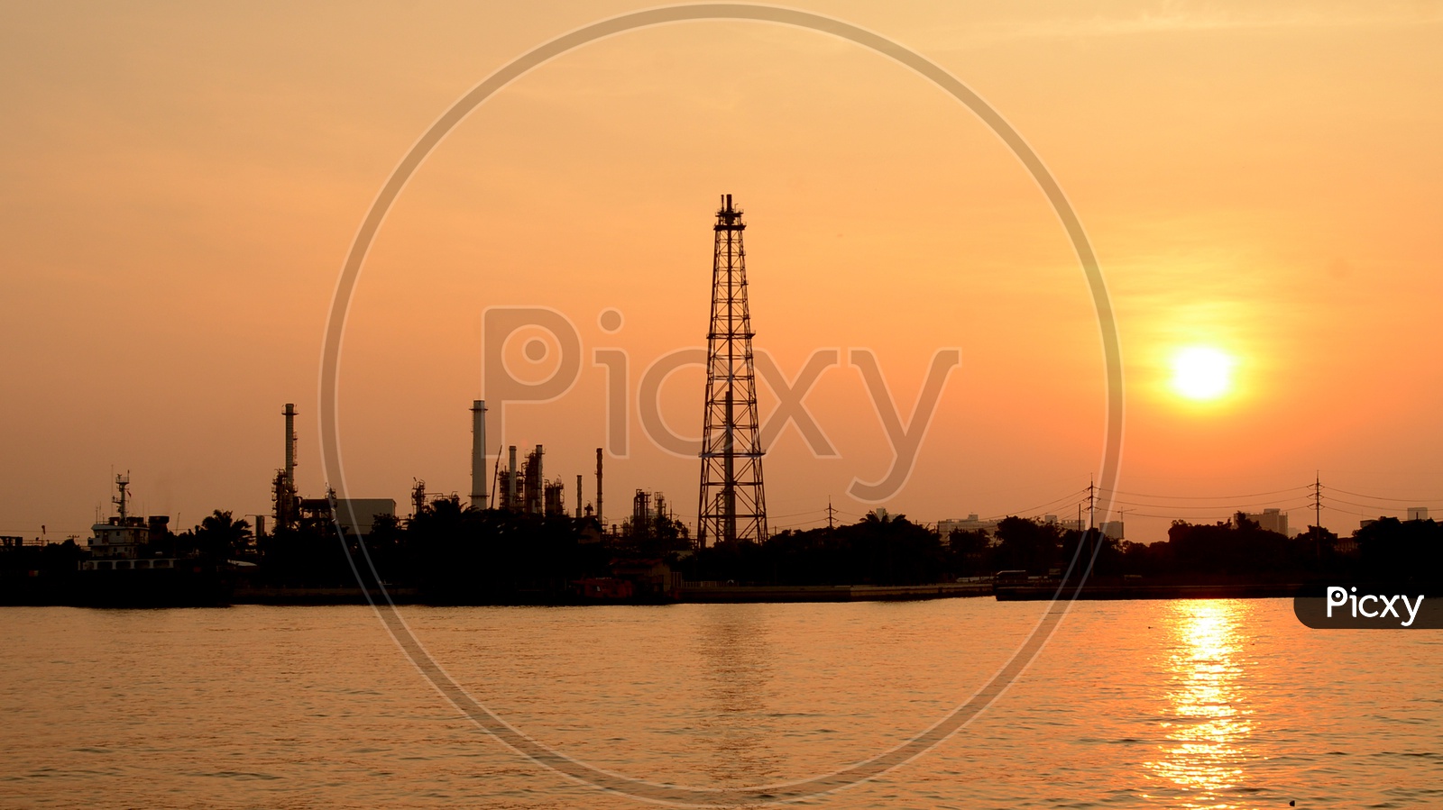Silhouette of Oil Refinery Plat With Exhaust Pipes And Towers of Industry over a Sunset Sky in Background