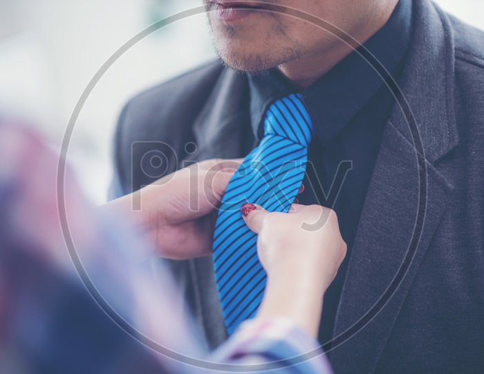 Close-up of a woman tying neckties to a man