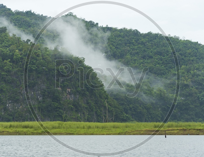 Tropical Lake View With Fog Clouds Over Green Mountains