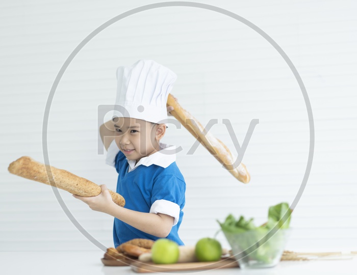 Boy as chef holding Italian long breads and enjoying cooking
