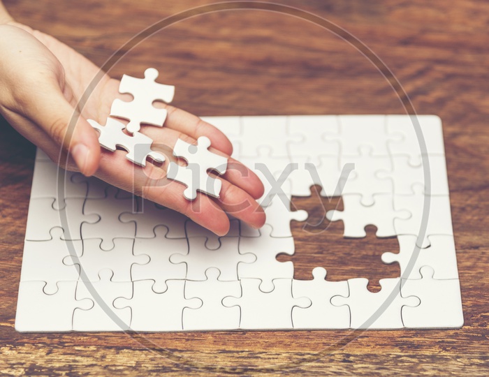 Close up of hand placing the jigsaw puzzle pieces, Hand holding missing jigsaw puzzle piece down in to the place, conceptual of problem solving, finding a solution