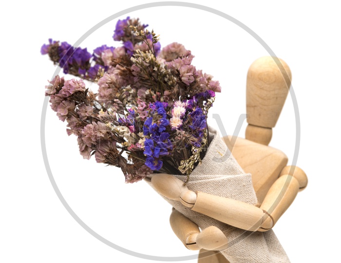 Dried vintage flowers are beautifully held by a wooden toy  placed on white ground.
