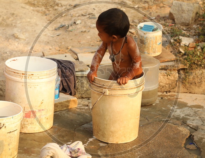 A Child playing with water in a bucket during shower