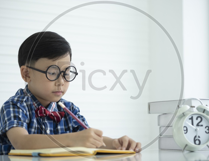 Portrait of a boy wearing spectacles and doing homework