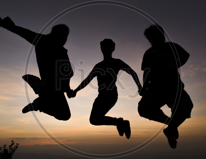 Silhouette of People Jumping In Joy Over a Sunset Sky