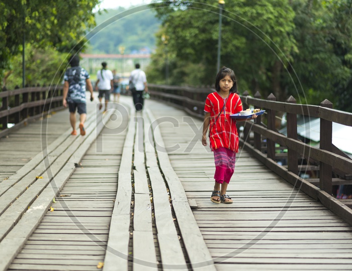 Cute Mon girls walking on wooden  bridge, longest wooden bridge in Mon village, Sangklaburi, Kanchanaburi, Thailand
