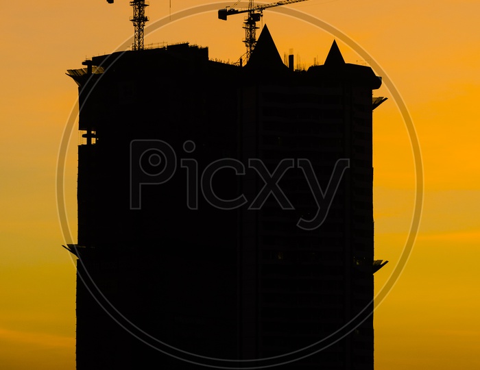 Silhouette Of High Rise Under Construction Buildings With Sunset Sky In Background