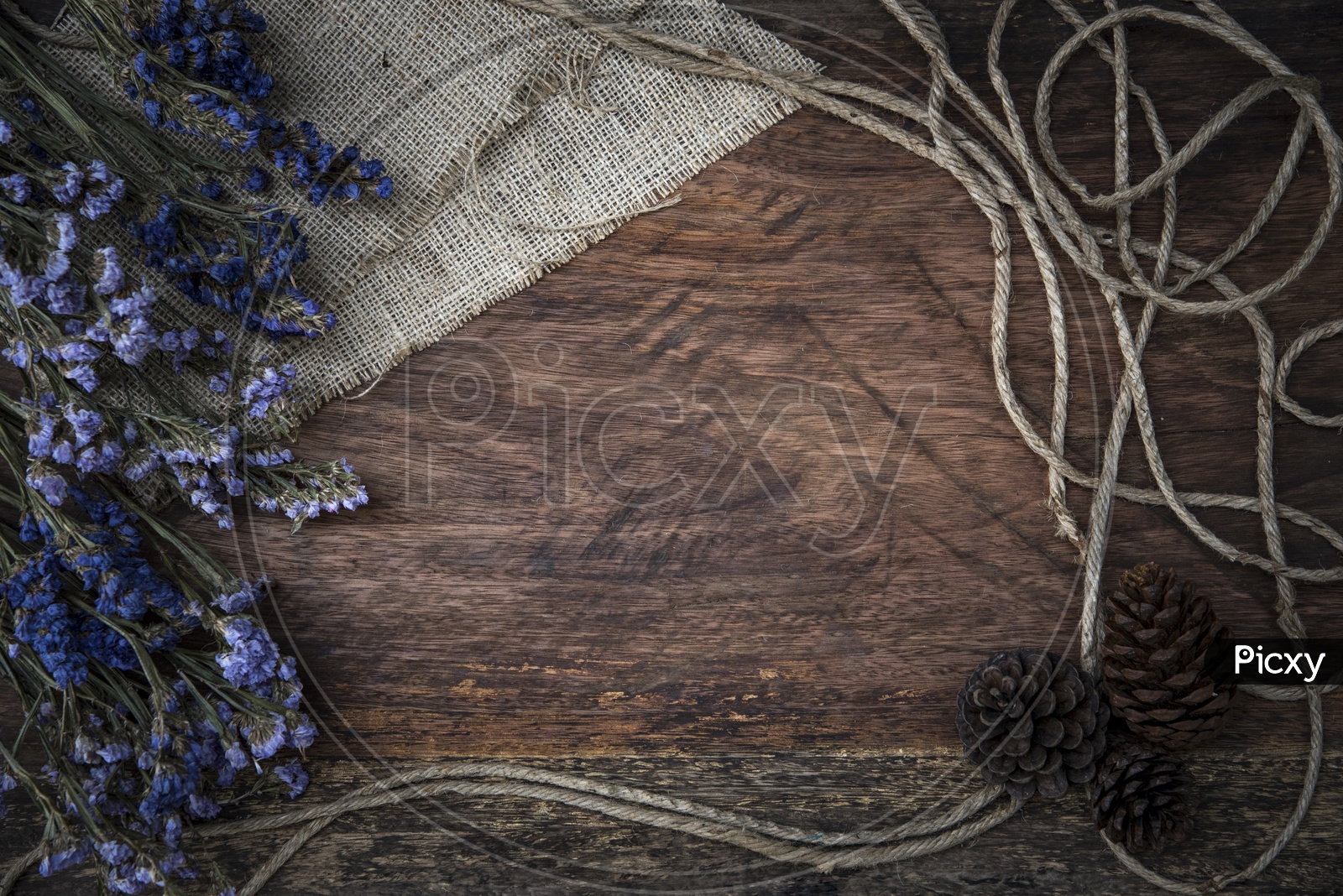 Purple dry flowers and jute threads on wooden board