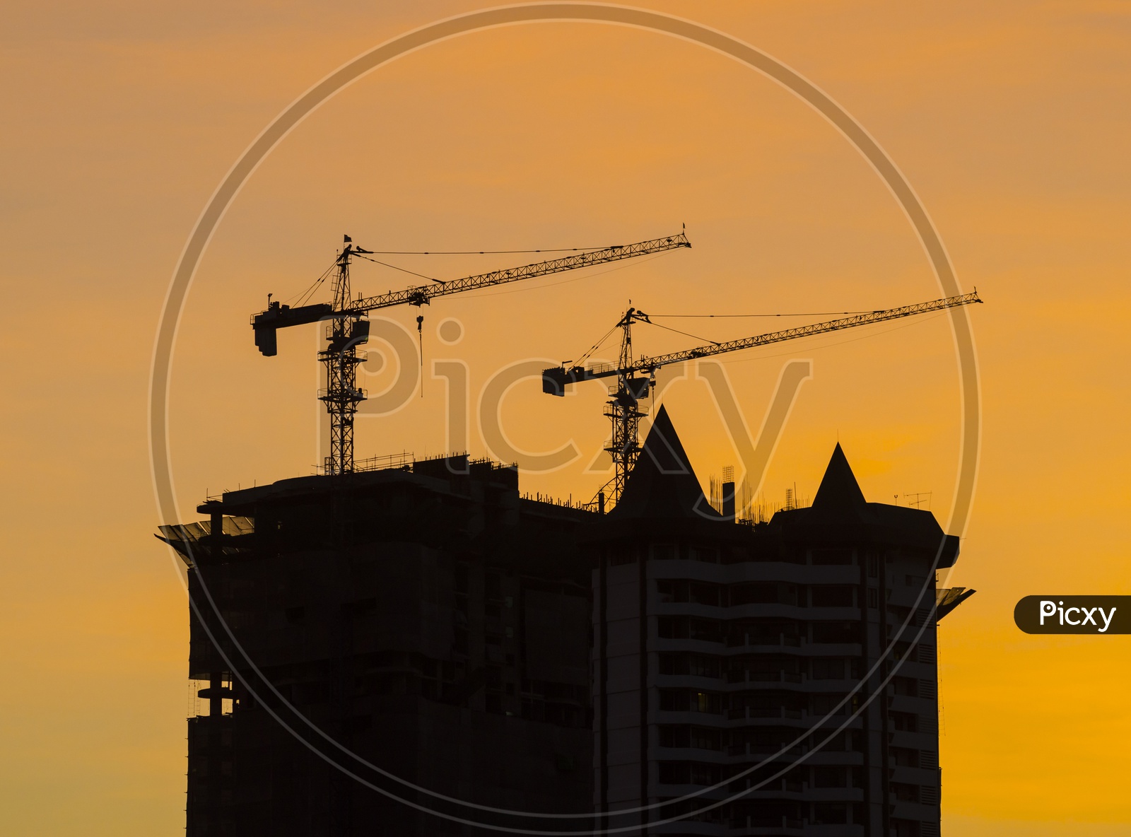 Silhouette Of High Rise Under Construction Buildings and Cranes  With Sunset Sky In Background