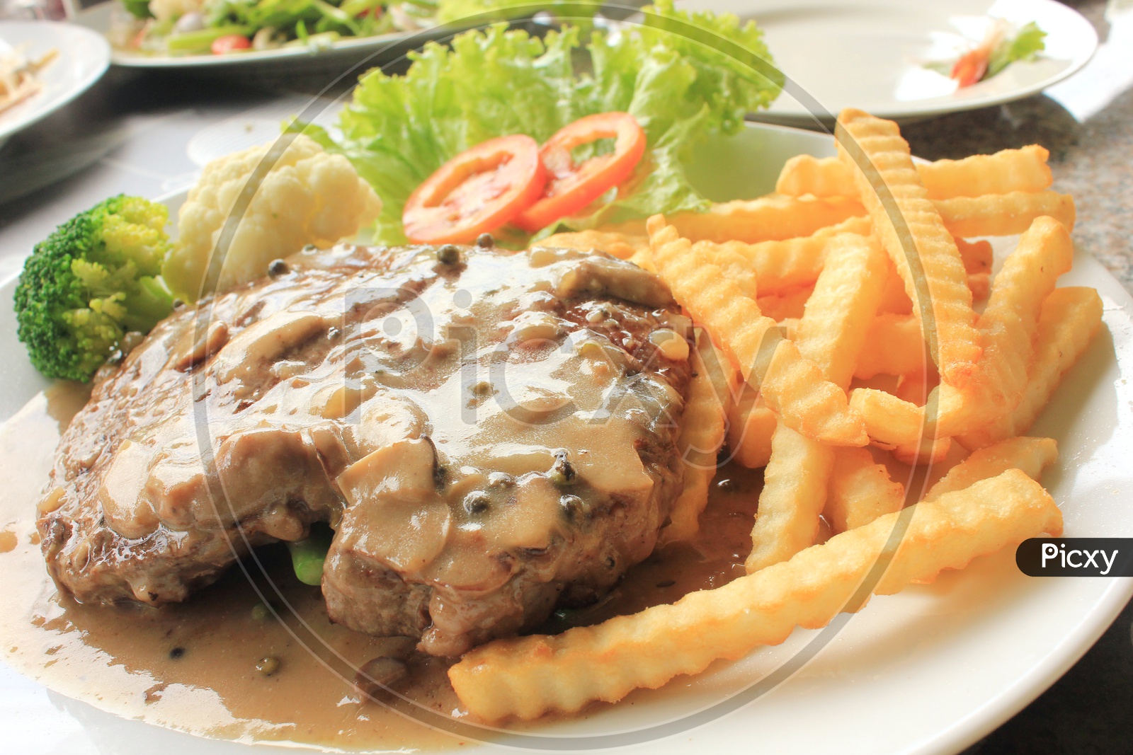 Thai Style Grilled Beef steak Garnished with French Fries in a Plate
