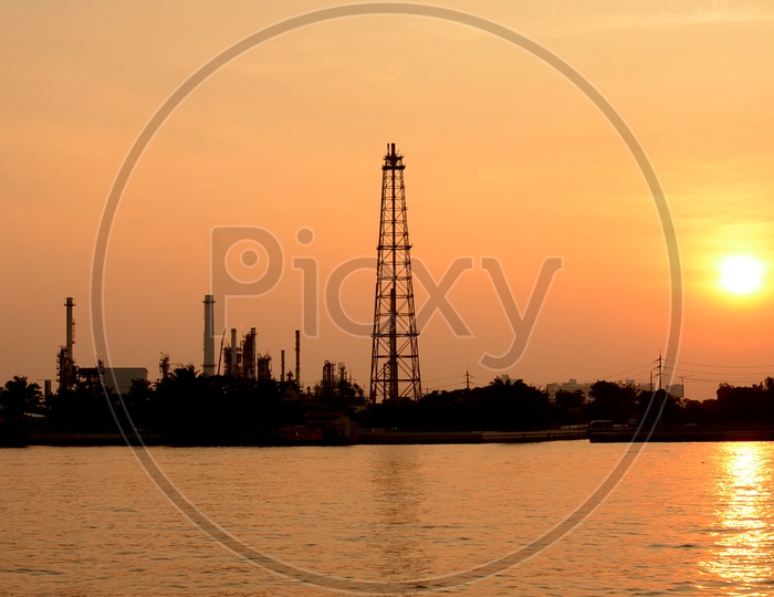 Silhouette of Oil Refinery Plat With Exhaust Pipes And Towers of Industry over a Sunset Sky in Background