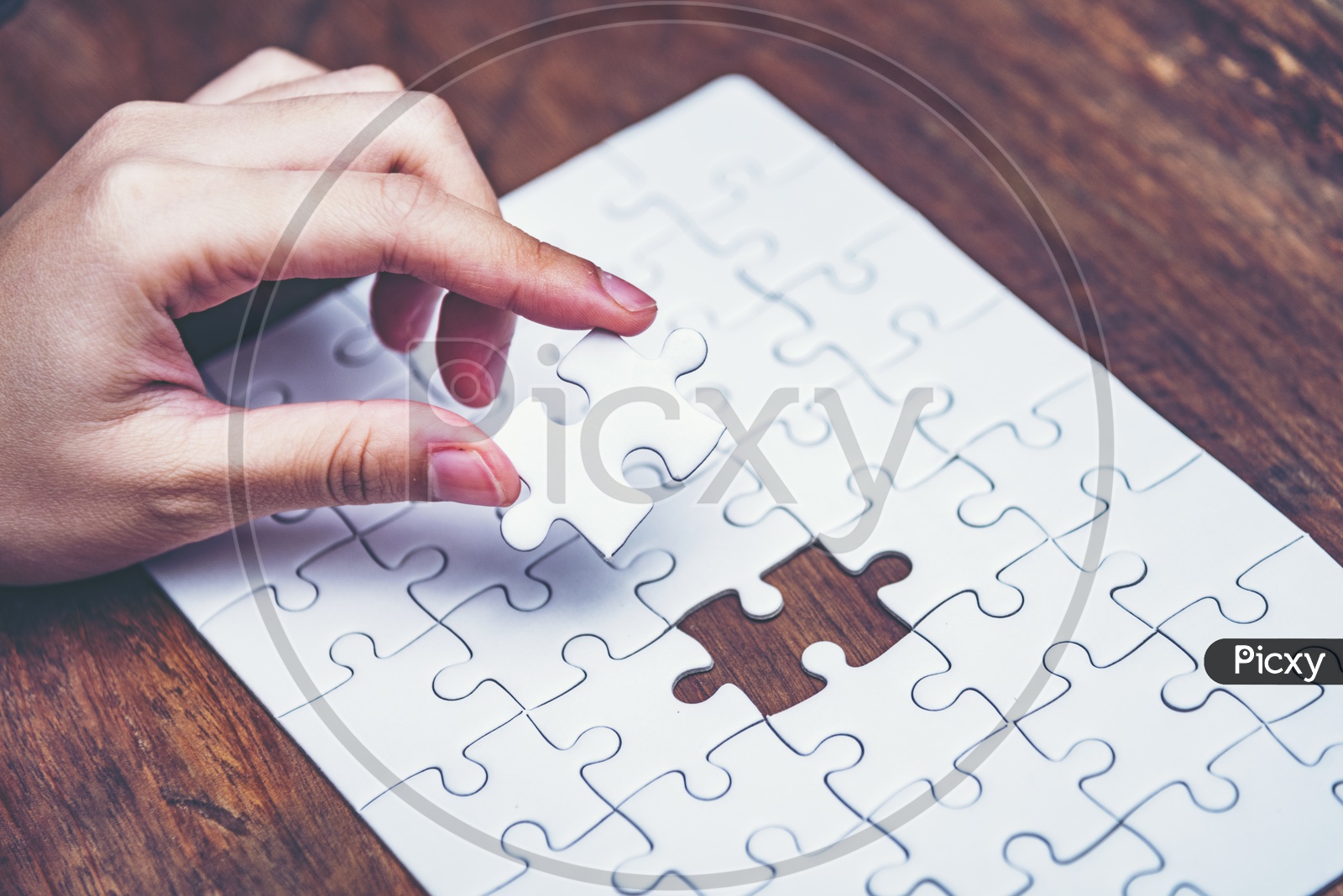 Close up of hand placing the last jigsaw puzzle piece, Hand holding missing jigsaw puzzle piece down in to the place, conceptual of problem solving, finding a solution